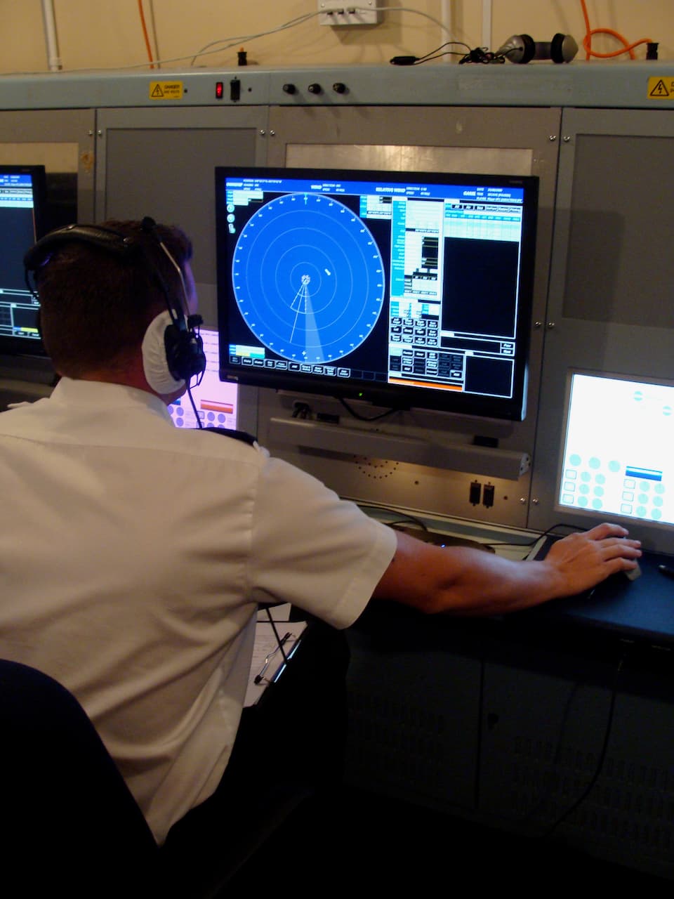 A participant operating an Airwaves console with a circular radar display and a separate touch-screen control panel.