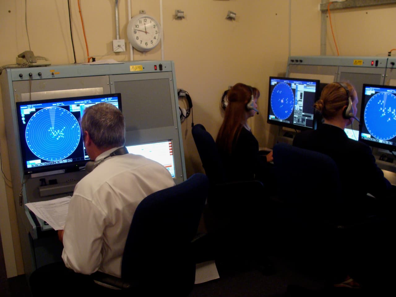 Participants wearing headsets at Airwaves simulator stations, with radar tracks visible on their screens.
